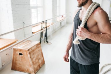 Hafif spor olarak omuz ip çalışma üzerinde tutarak yakışıklı kaslı adam. Fitness spor salonu çapraz savaş ipleri adamla portresi