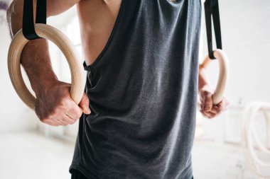 İş günü içinde jimnastik yüzük spor salonu çapraz yapıyor Erkek jimnastikçi görünümü kapatın. Crosstraining halkalar ışık salonunda atlet egzersizleri uygun