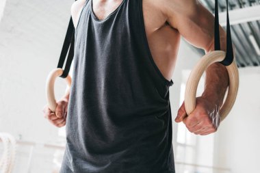 Crossfit spor salonu jimnastik halkaları üzerinde egzersiz yaparak güçlü adam. Hafif spor salonu içinde jimnastik yüzük üzerinde eğitim uygun erkek atlet
