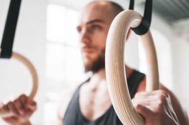 Güçlü adam crossfit spor salonu jimnastik halkaları üzerinde egzersiz yaparak görünümü kapatın. Hafif spor salonu içinde jimnastik yüzük erkek atlet egzersiz uygun