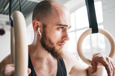Dinlenme ve hafif spor salonunda jimnastik halkaları tutan sakallı erkek atlet. Uygun adam rahatlatıcı jimnastik kez çaldıktan sonra yoğun çalışma üzerinde