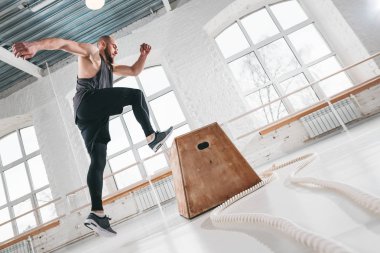 Güçlü fitness adam spor salonu kutusunda atlama egzersizleri yapıyor. Spor giyim ve spor salonu kutusunda üstünden atlayarak fit atlet