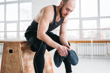 Terli kutusu ve tutun havluda el yoğun çapraz egzersiz yaptıktan sonra oturan adam uygun. Fitness atlet spor salonunda dinlenme