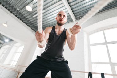 Savaş kullanarak uygun adam atlet egzersizleri hafif spor salonu için ipleri. Spor salonunda egzersiz çapraz için eğitim halatlar kullanarak güçlü fitness sporcu