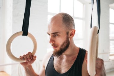 Erkek atlet spor salonunda jimnastik halkaları tutan. Fitness adam spor salonu içinde jimnastik yüzük üzerinde asılı 