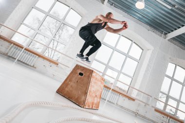 Güçlü fitness adam spor salonu kutusunda atlama egzersizleri yapıyor. Spor giyim ve spor salonu kutusunda üstünden atlayarak fit atlet