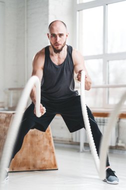 Savaş kullanarak uygun adam atlet hafif spor salonunda egzersiz için ipleri. Spor salonunda egzersiz için eğitim halatlar kullanarak güçlü fitness sporcu