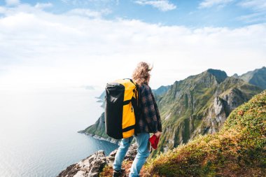 Yüksek dağda sırt çantası ile Tek başına profesyonel gezgin kenar uçurum kaya üzerinde duran ve uzağa bakıyor. Macera yaşam tarzı tatil