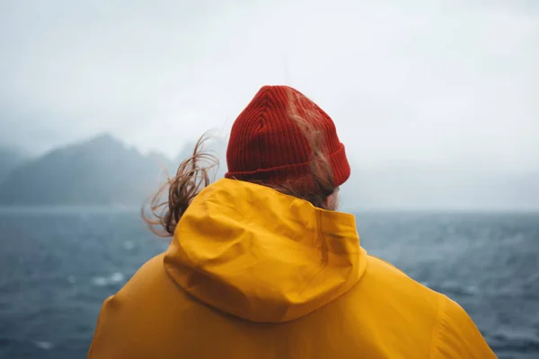 폭풍우가 몰아치는 바다를 바라보는 모자와 노란색 비옷을 힙스터 여행자 스칸디나비아 — 스톡 사진
