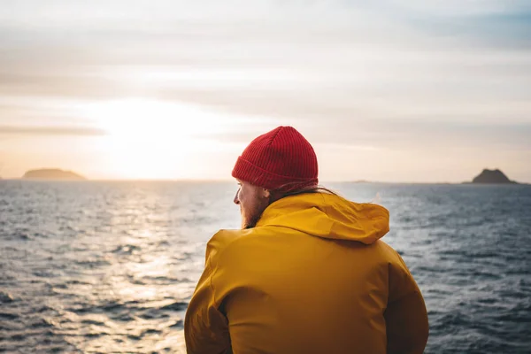 하늘에 바다와 산을보고 아름다운 바다를 즐기는 노란색 비옷과 모자를 힙스터 — 스톡 사진