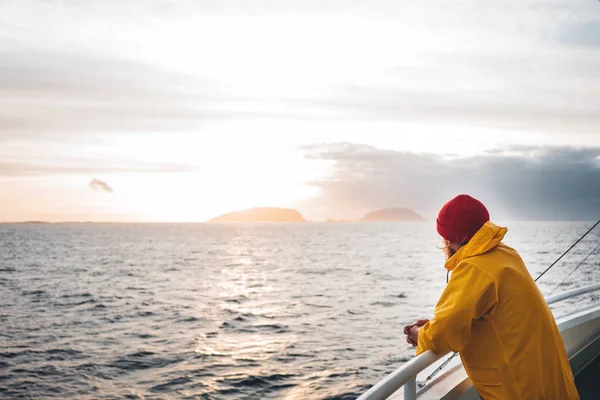 바다를 바라보는 모자와 노란색 비옷을 힙스터 여행자 스칸디나비아 풍경에서 — 스톡 사진