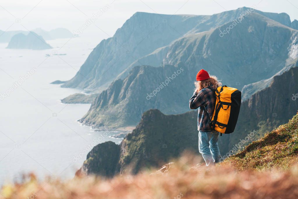 Alone man expeditor wearing professional backpack standing on the edge cliff mountain above sea and looking on epic high landscape. Lifestyle adventure vacation