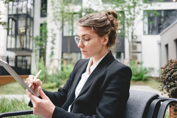 Businesswoman at cafe on veranda using gadgets for digital work. Young business woman sitting at coffee shop working on digital tablet.