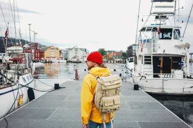 Tek başına gezgin rıhtım manzarası ile şehir sokaklarında yürüyor. Yolculuk sırasında sırt çantalı turistin arka görüntüsü