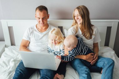 Baba dizüstü bilgisayarda çalışırken bir bebeğe bakan genç anne. Evde aile