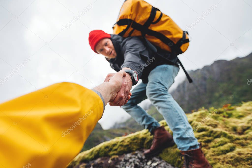 POV view on brave tourist helping his active friend holding to hand climbing to rock. Two travelers climb to mountains lifestyle outdoor vacation
