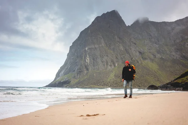 Άνθρωπος Τυχοδιώκτης Περπατά Στην Παραλία Της Θάλασσας Ανάμεσα Συννεφιασμένα Βουνά — Φωτογραφία Αρχείου
