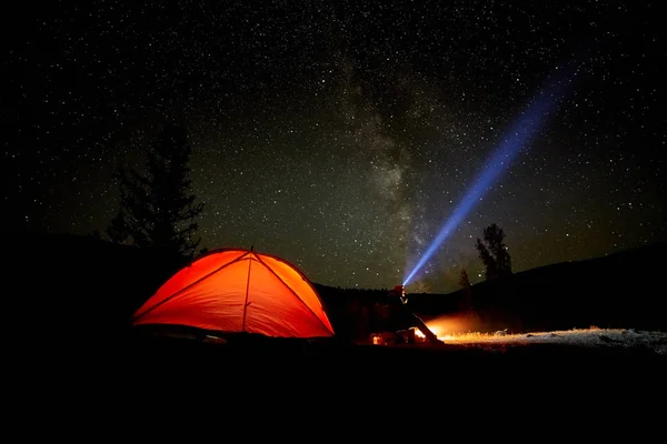 En turist klockor stjärnklara himlen nära tältet på bakgrund av en vacker och slingrande flod. — Stockfoto