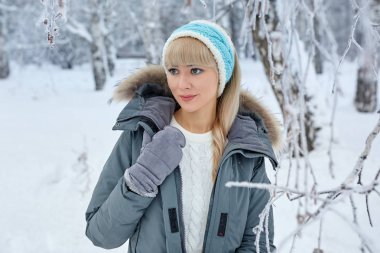 Uzun kıvırcık saçlı ve beyaz giysiler açık kar taneleri altında kış ormandaki eğleniyor güzel kız.