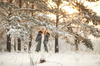 Uzun kıvırcık saçlı ve beyaz giysiler açık kar taneleri altında kış ormandaki eğleniyor güzel kız.
