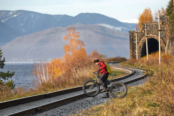 Tourist rides a bike with wide wheels along the shore of Lake Baikal.