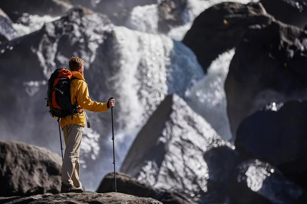 Lycklig man med ryggsäck njuter av fantastiska vattenfall resor livsstil och framgång konceptet semester i den vilda naturen — Stockfoto