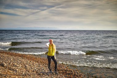 Güzel kız sahil üzerinde yürür. Seyahat ve tatil. Özgürlük kavramı. Şehvetli sarışın güzel kadın, mükemmel bir vücut ve uzun sağlıklı saç ile kız