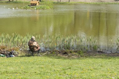 gölde oturan olta çubukları ile balıkçı