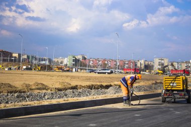 Turuncu tulumlu işçi 3 numaralı yolu onarıyor.