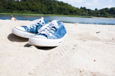 beyaz kum üzerinde mavi spor ayakkabı