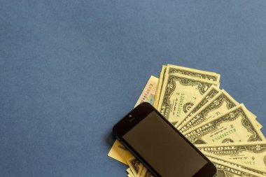 kağıt para ve siyah bir arka plan üzerinde yatan bir cep telefonu