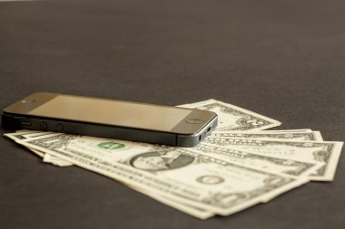 kağıt para ve siyah bir arka plan üzerinde yatan bir cep telefonu