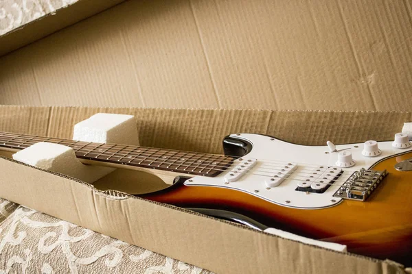 electric guitar is in a cardboard box