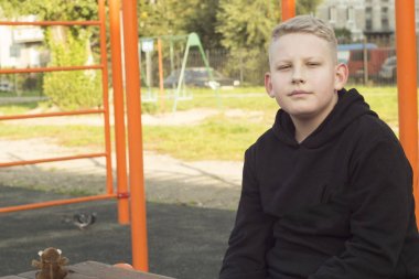 sarı saçlı tema ceket genç adam Playground oturuyor