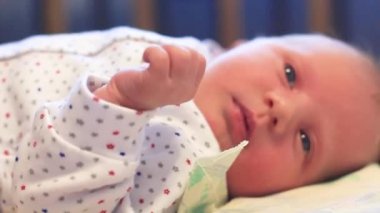 çocuk sırt üstü yatar ve yuvarlanmaya çalışır. bir çocuk diğer yönde sallanan