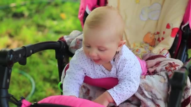 Новорожденная девочка сидит в коляске и играет с одеялом — стоковое видео
