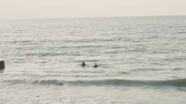 deniz dalgaları dalgakıranlarda yuvarlanıyor.sörfçüler tahtalarda yüzüyor