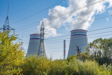 elektrik santralinin dumanlı bacaları mavi gökyüzüne karşı duruyor