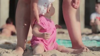 Küçük kız kumsalda kumla oynuyor.