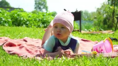 Sarı saçlı küçük bir kız açık bir alanda yatıyor.