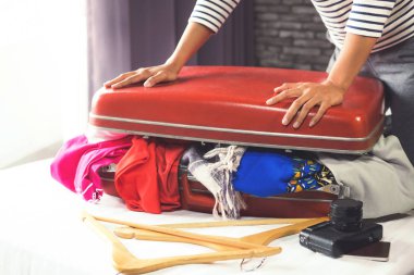 Seyahat ve tatil kavramı, mutluluk genç kadın elbiselerini ve malzeme bir sürü bavul yatak içine ambalaj tatil seyahat ve yolculuk yolculuk için hazırlamak.