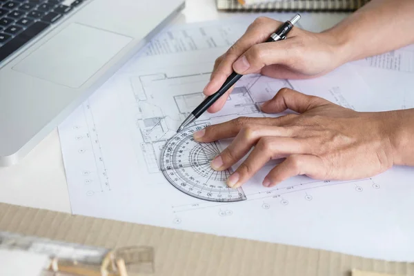 Architect working on blueprint, Engineer working with engineering tools for architectural project on workplace, Construction concept - building project, blueprints, ruler and dividers.