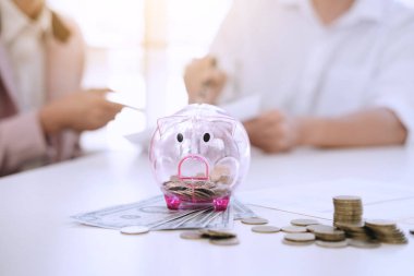 İki rapor yazma ve hesap makinesi analizi iş yatırım stratejisi için para sikke ve Doları, mali kavramı gelir ile kullanarak kumbara içine koyarak paralar çiftler.