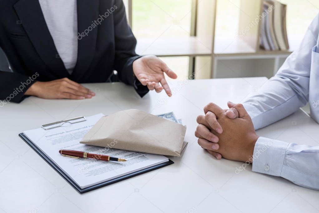 Bribery and corruption concept, bribe in the form of dollar bills, Businessman giving money in the envelope while making deal to agreement a real estate contract and financial corporate.