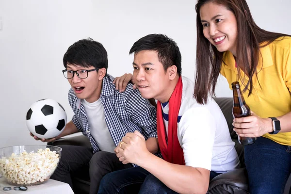 Group of friends fanclub watching soccer match on tv and cheering football team, celebrating with beer and popcorn at home, sports and entertainment concept.