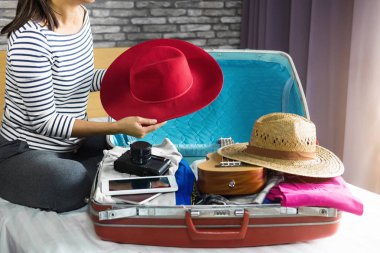 Seyahat ve tatil kavramı, mutluluk genç kadın elbiselerini ve malzeme bir sürü bavul yatak içine ambalaj tatil seyahat ve yolculuk yolculuk için hazırlamak.