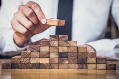 İş büyüme kavramı ile ahşap blok yapmak için riske, adamın elini kadar kazık vardır ve bir ahşap blok istifleme, alternatif risk kavramı, plan ve strateji otelde iş.