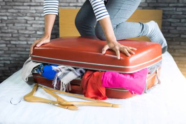 Seyahat ve tatil kavramı, mutluluk genç kadın elbiselerini ve malzeme bir sürü bavul yatak içine ambalaj tatil seyahat ve yolculuk yolculuk için hazırlamak.