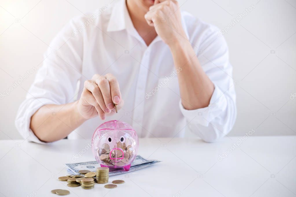 Businessman putting coins into piggy bank and using calculator to analysis business investment strategy with income of money coin and dollar, financial concept.