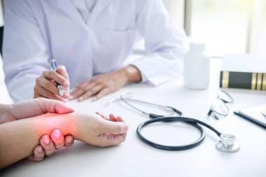 Doktor alarak ve muayene sırasında hastanın bilek ağrı kontrol beyaz ceket.